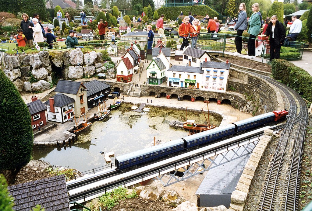 Miniature houses and a rail track in a model village in Beaconsfiled UK, with people visiting